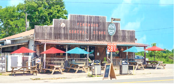 A rustic wood general store with red and turquoise umbrellas in front from My Pinewood Kitchen