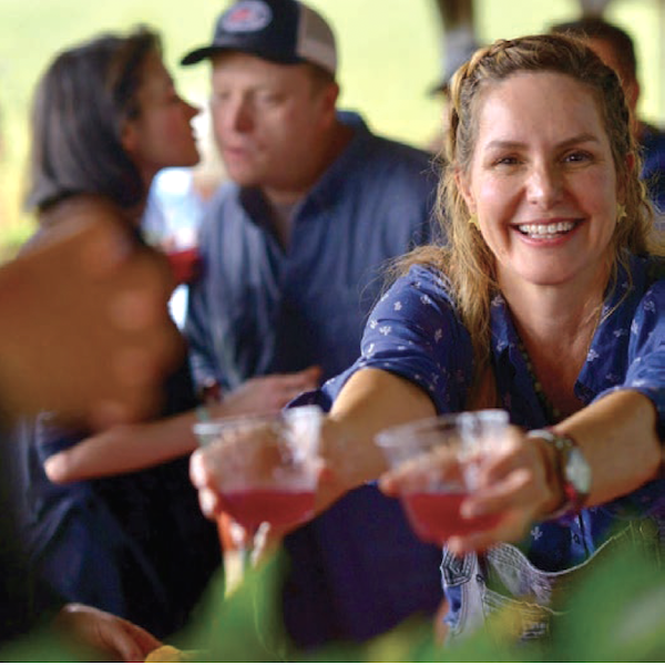 A woman serving red drinks in wine glasses