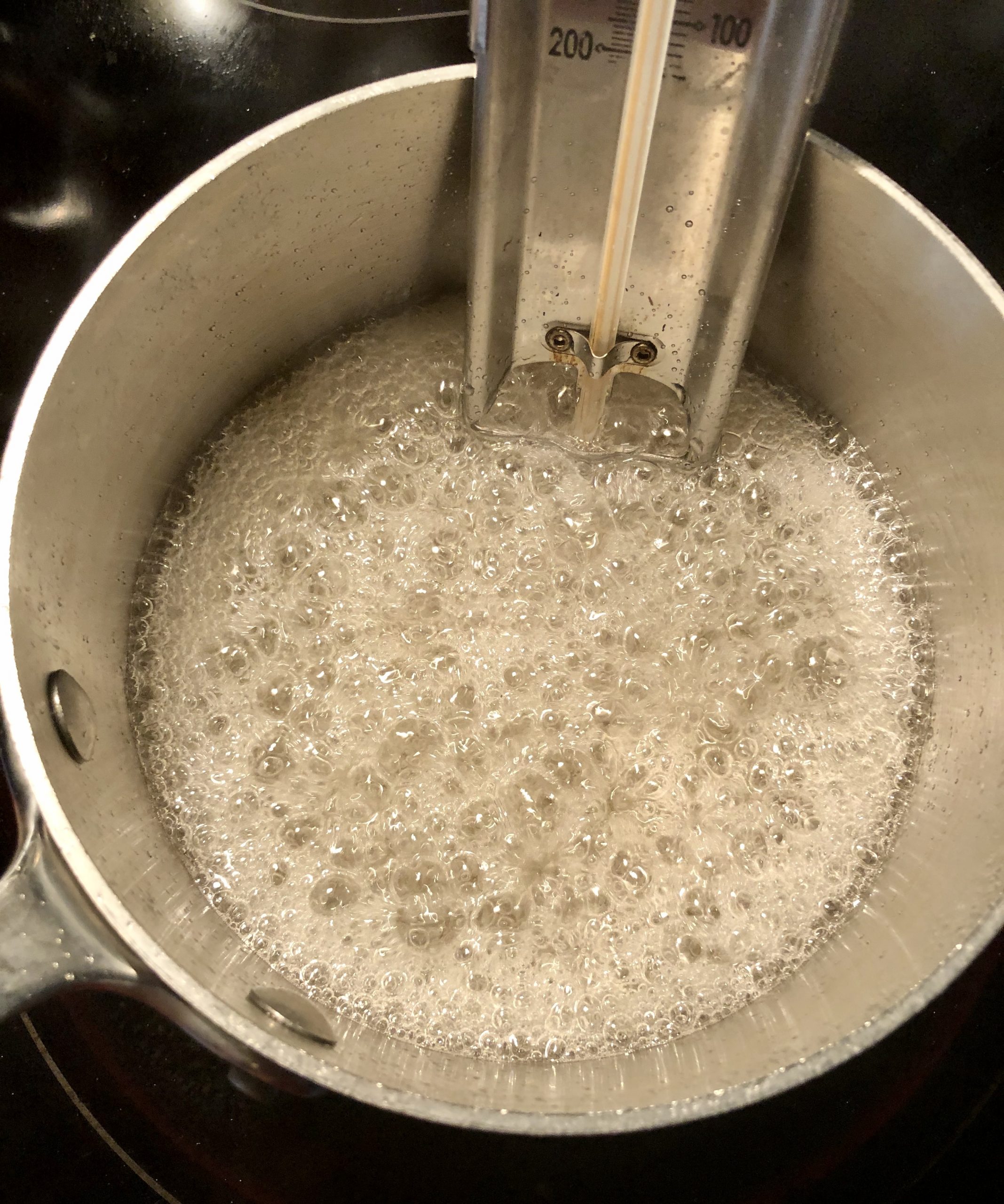 A saucepan filled with bubbling sugar syrup fitted with a candy thermometer for Salted Chocolate Covered Halvah