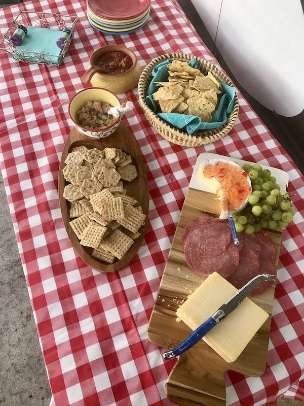 Red and white checkered cloth covered table with charcuterie, salsa and chips from Living Our Dream