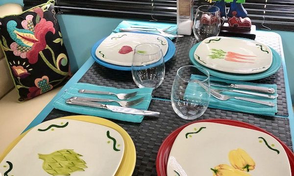 A table set with colored plates that are topped with hand painted salad plates from Living Our Dream
