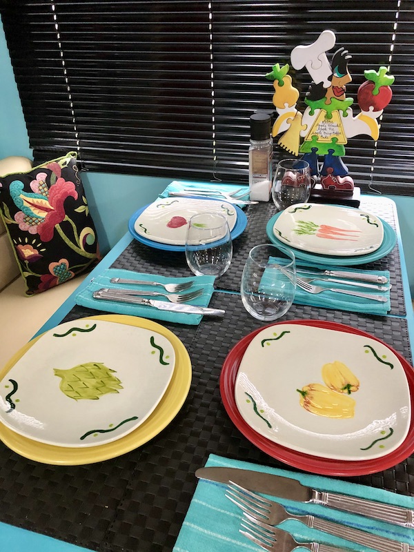 A table set with colored plates that are topped with hand painted salad plates from Living Our Dream