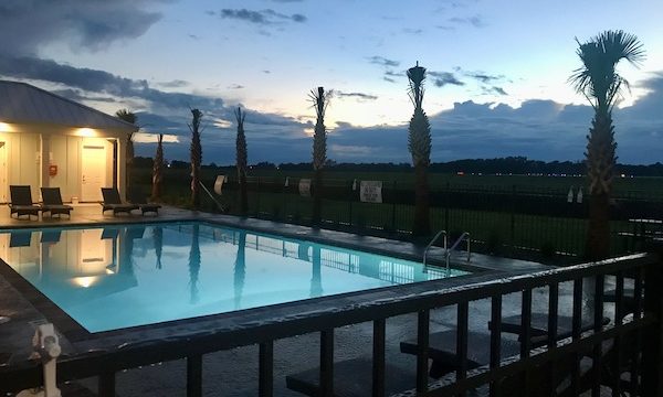 A swimming pool at dusk with palm trees at Barefoot RV Resort North Myrtle Beach