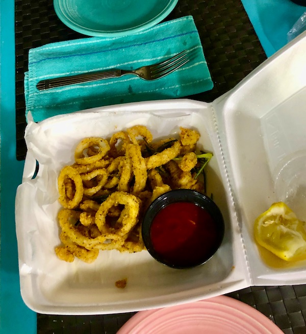 A take out container with fried calamari rings with red sauce and lemon from Francesco's Ristorante