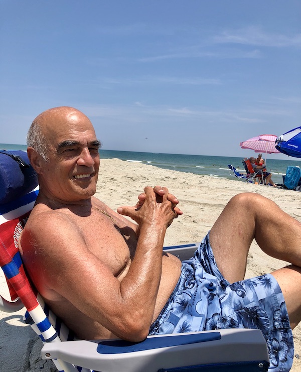 A man in a blue bathing suit sitting on a beach from RVing With Family