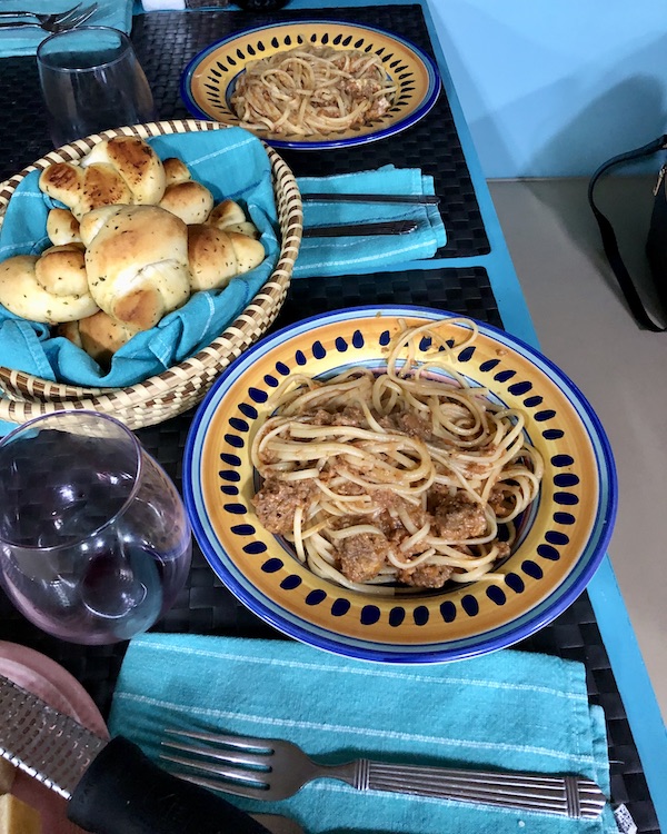 A table with plates of linguine with meat sauce and a basket of garlic knot rolls from RVing With Family