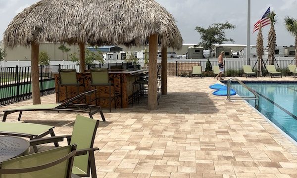 A tiki hut, pool, paver deck and seating at Sunkissed Village RV Resort