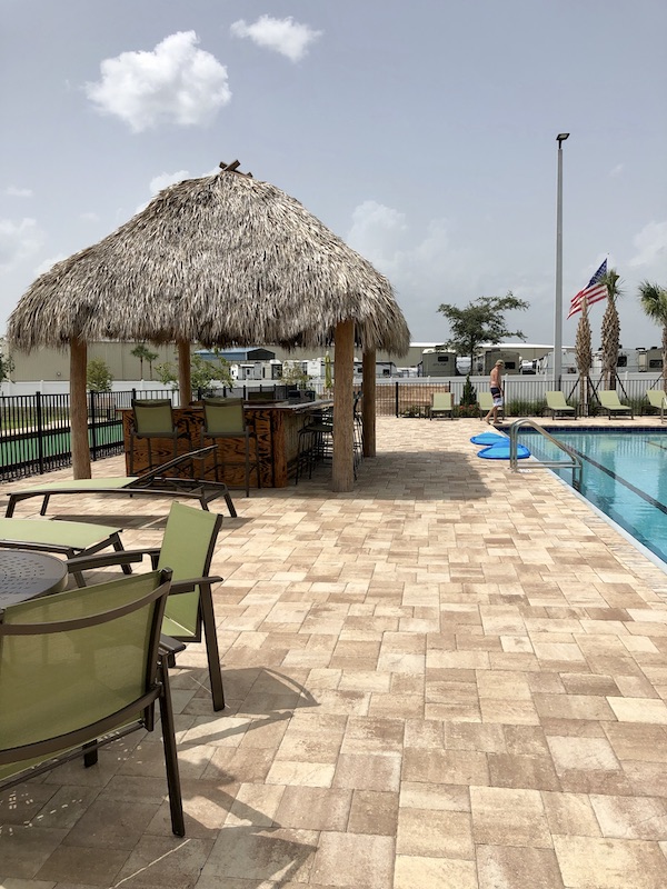 A tiki hut, pool, paver deck and seating at Sunkissed Village RV Resort