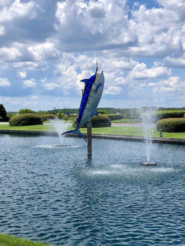 A sculpture of a large fish coming out of the water with fountains in OBX Outer Banks North Carolina