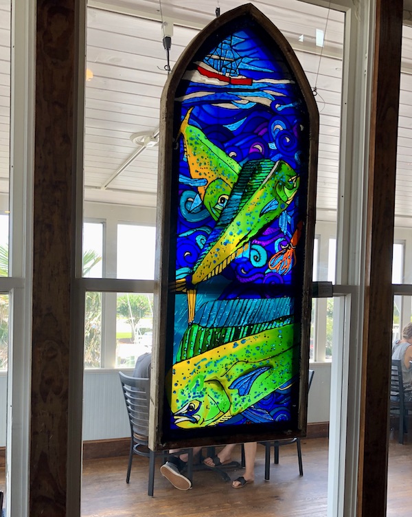 A stained glass panel of sea life in vibrant green and blue in a restaurant in OBX Outer Banks North Carolina