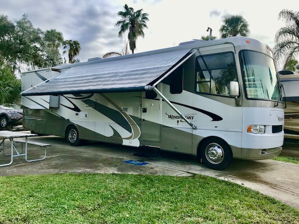 The side of a white and tan RV with the awning out from RV Renovations Complete The Big Reveal