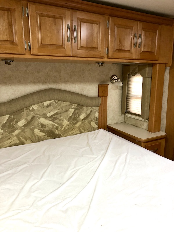 An RV bedroom with cloth headboard and window treatments from RV Renovations Complete The Big Reveal