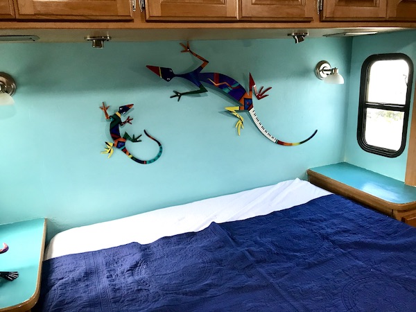 An RV bedroom with colorful lizards above the bed from RV Renovations Complete The Big Reveal