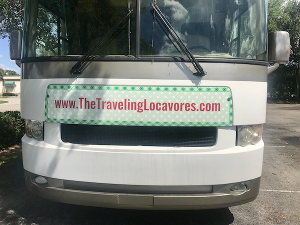 The front of an RV with green graphics and red writing from RV Renovations Complete The Big Reveal