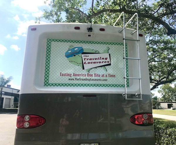 The back of an RV with a logo and green plaid graphics from RV Renovations Complete The Big Reveal