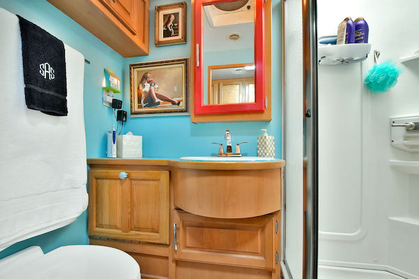 An RV bathroom with wood vanity and turquoise walls from RV Renovations Complete The Big Reveal