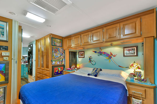 An RV bedroom with lots of art hanging from RV Renovations Complete The Big Reveal