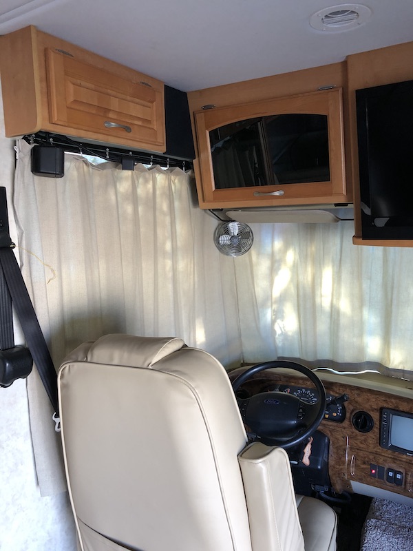 The cockpit of an RV with cream colored curtains from RV Renovations Complete The Big Reveal