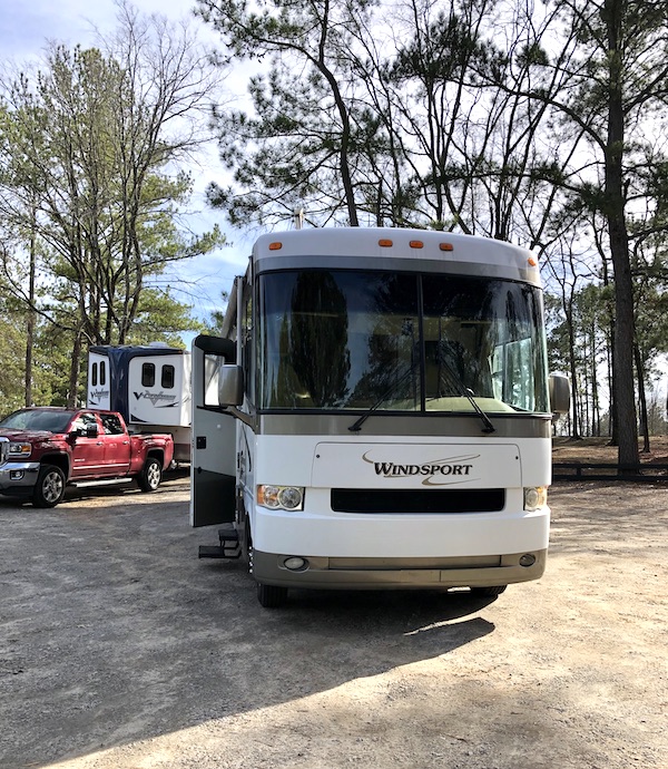 The front of a white and tan RV with trees in the background from RV Renovations Complete The Big Reveal