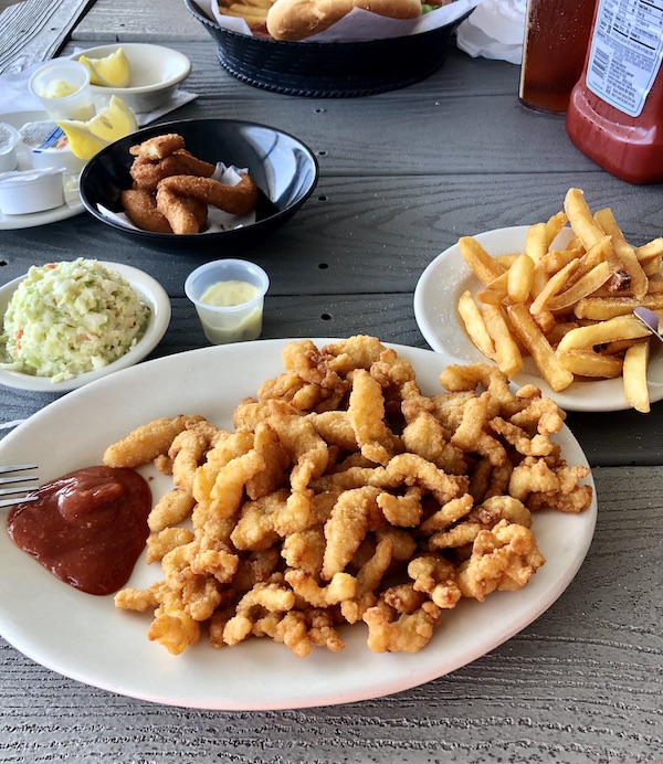 A plate piled high with fried clam strips also a dish of coleslaw and a plate of French fries at Sanitary Restaurant, Morehead City, NC