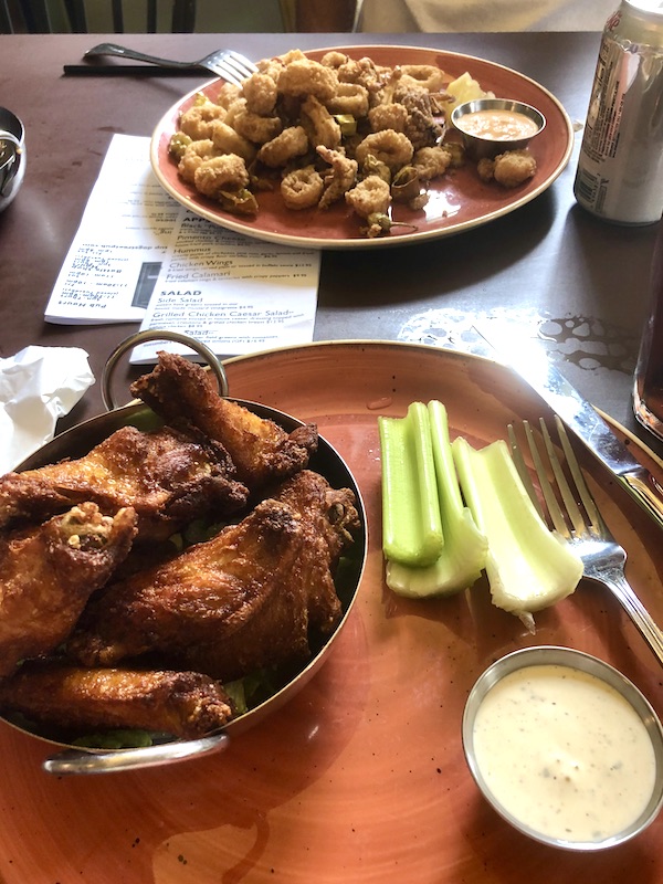 A rust colored platter topped with chicken wings, celery and blue cheese sauce in Williamsburg Virginia