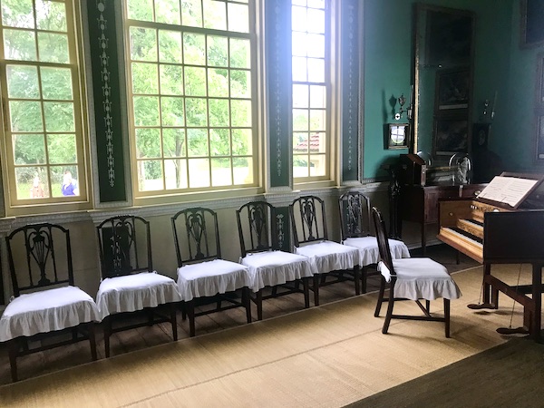 A huge room with green walls, wood floor, lots of windows and a row of chairs at George Washington's Mount Vernon