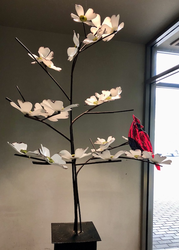 A glass dogwood tree with a glass cardinal on a branch at the Norfolk Botanical Gardens