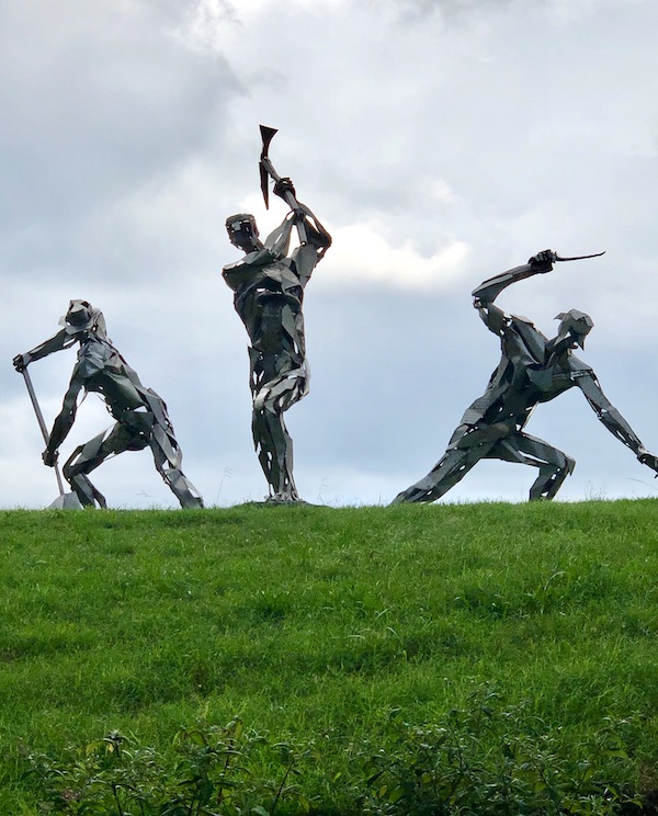 A trio of steel sculptures on a lawn depicting laborers at the Norfolk Botanical Gardens