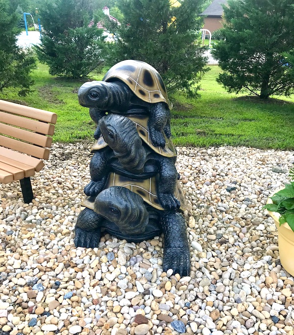 A sculpture of 3 tortoises on top of each other on gravel near The Torpedo Factory Alexandria Virginia