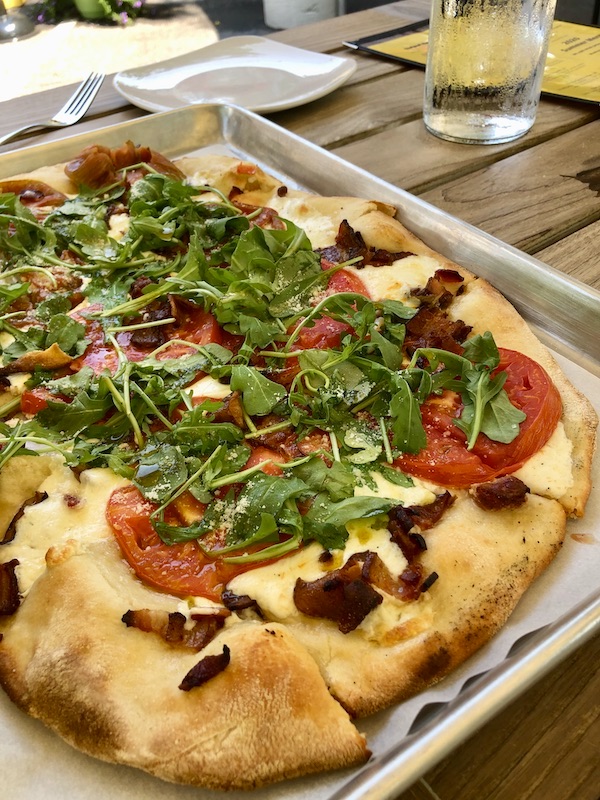 A pizza topped with red tomato slices and basil at Vin 909 in Annapolis Maryland