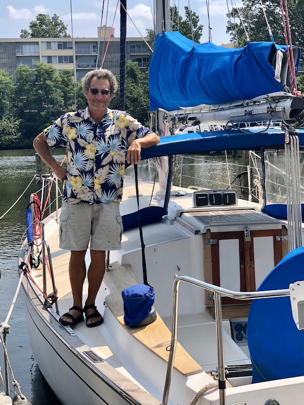 A man in shorts and a print shirt on a sailboat in Washington DC and Annapolis Maryland