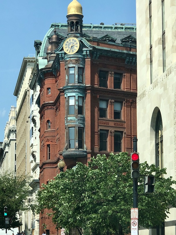 A huge red brick building with a clock in the corner, flanked by two tall white buildings in Washington DC and Annapolis Maryland