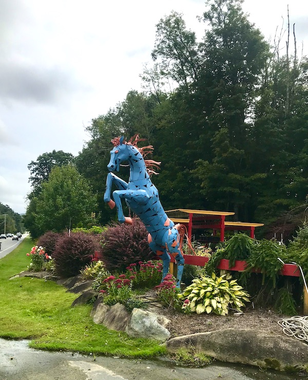 A blue and pink metal horse sculpture in a garden near the Blue Ridge Parkway NC