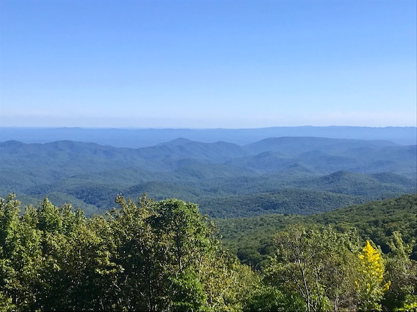 Trees in the foreground, mountain ranges and sky along the Blue Ridge Parkway NC