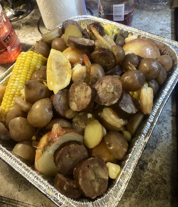 A foil pan filled with cooked potatoes, sausage, shrimp and corn at Delaware Seashore State Park