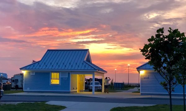 A gorgeous sunset in pink, coral, yellow and lavender behind a small building at Delaware Seashore State Park