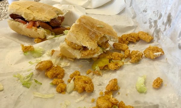 A pair of submarine sandwiches with small fried shrimp spilling out onto white deli paper in LaPlace Louisiana