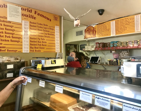 A deli counter with a woman, wearing a PPE mask, serving a customer in LaPlace Louisiana