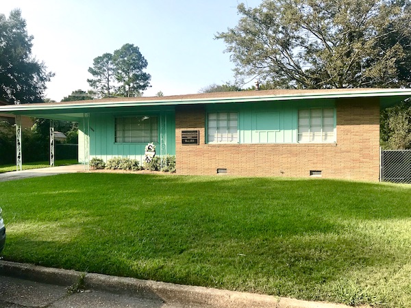 A turquoise wood and brick ranch house with lawn near the Mississippi Civil Rights Museum