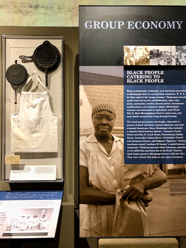 A display of cast iron skillets, a chef's apron, a cook and wording at the Mississippi Civil Rights Museum