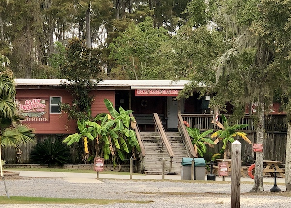 A tan building, Cajun Encounters, with trees along our drive from NOLA to Biloxi