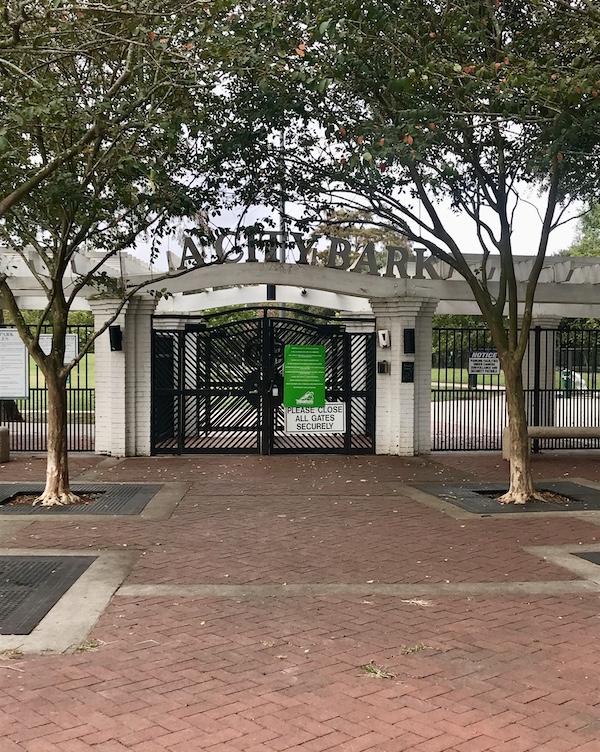 A gateway to a New Orleans City Park with trees and red paver walkway