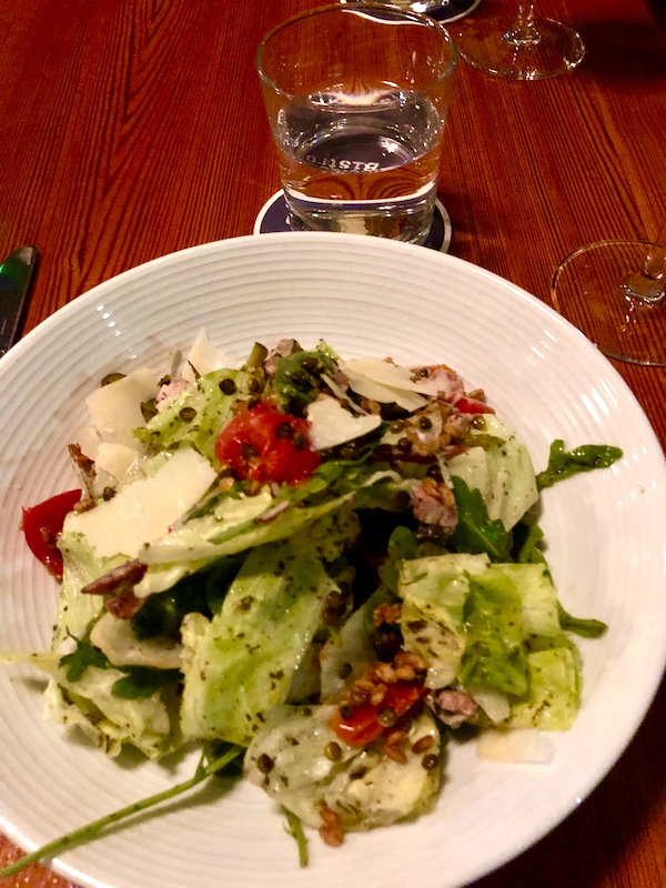 A white plate topped with a salad of mixed lettuces and tomato at Revisiting Bywater American Bistro
