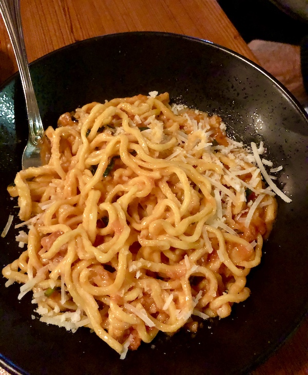 A matte black bowl filled with noodles in red sauce at Revisiting Bywater American Bistro