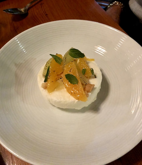 A white plate topped with a round frozen disc with orange slices and mint on top at Revisiting Bywater American Bistro