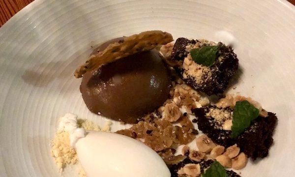 A white plate topped with scoops of brown and white ice cream and chopped nuts at Revisiting Bywater American Bistro