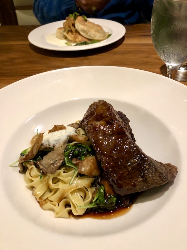 Beef short rib, noodles, mushrooms and greens on a white plate at Sue Zemanick's Zasu