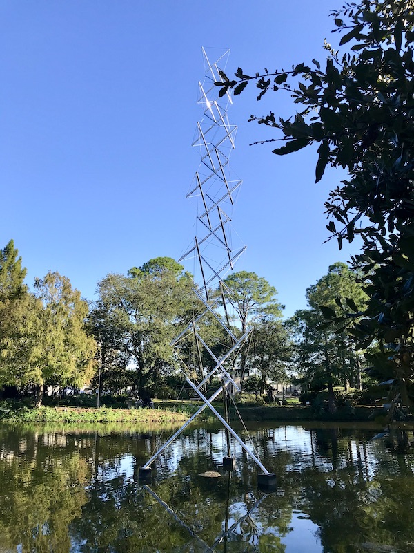 An airy stainless steel sculpture coming out of the water at the Bestoff Sculpture Garden