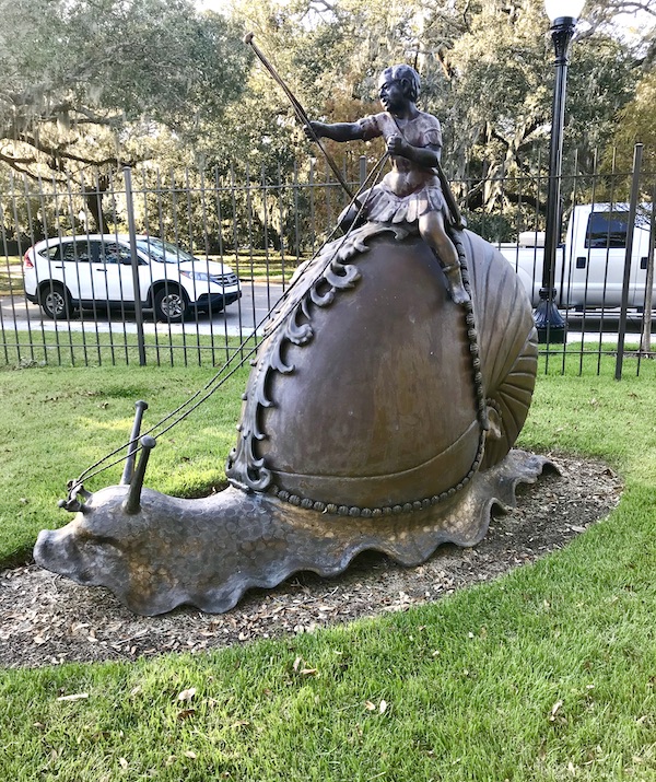 A bronze snail sculpture with a rider at the Bestoff Sculpture Garden