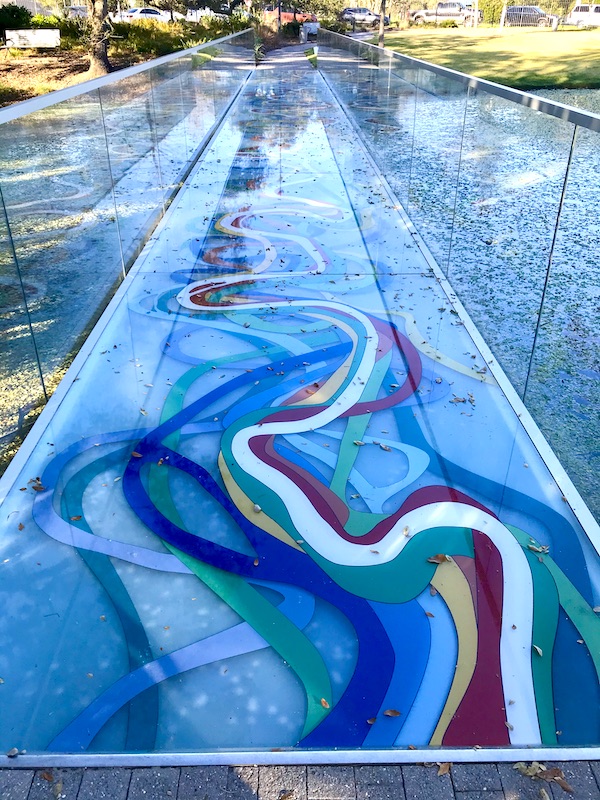 A glass bridge with meandering ribbons of color at the Bestoff Sculpture Garden